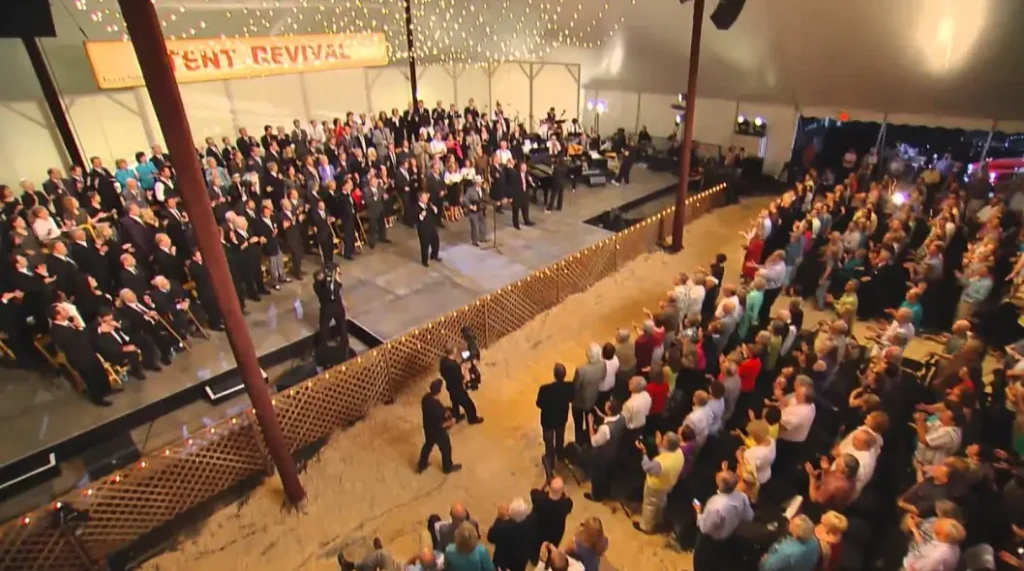 Large crowd at an indoor event with stage and audience seating.