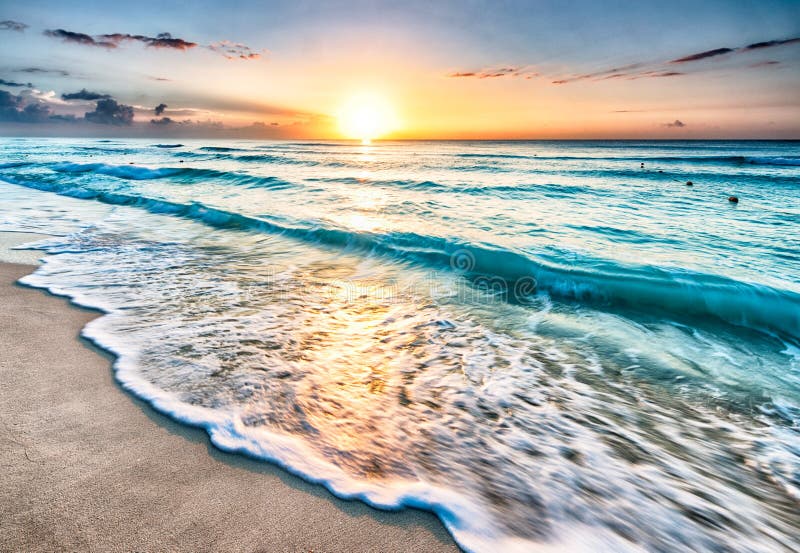 Sunrise over turquoise ocean waves on beach